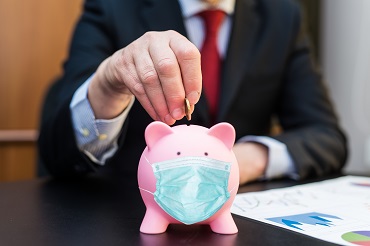 Man in suit inserting a coin on a piggy bank with mask