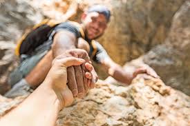 Article cover of man assisting a hand in rock climbing in color