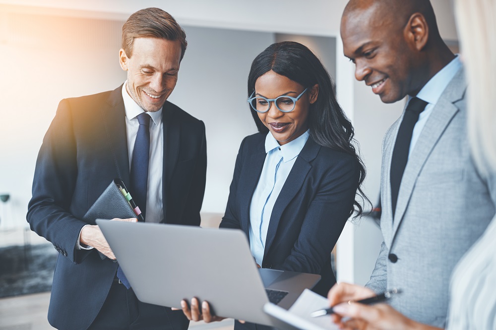 African business woman center surrounded by business men looking at a laptop