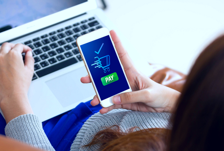 Woman with a laptop and a phone with pay image on screen