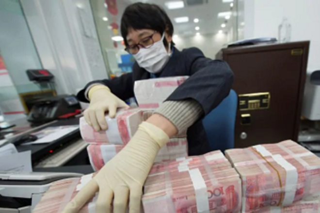 A bank employee wearing a mask arranges stacks of Chinese yuan notes at a bank in Nantong, Jiangsu province, China on Jan 30, 2020.PHOTO: REUTERS