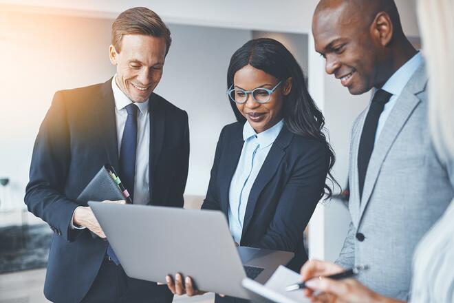 African business woman center surrounded by business men looking at a laptop