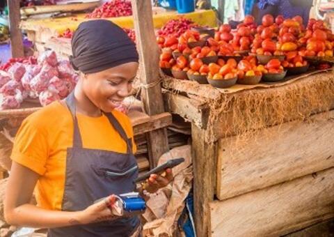 Woman selling fruits in a market using mobile payment 
