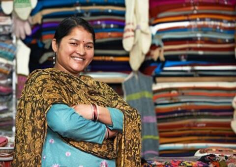 Indian woman smiling in front of a clothing store